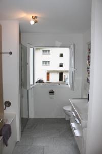 a bathroom with a sink and a toilet and a window at Apartment Beeli in Splügen