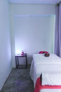 1 dormitorio con 2 camas y mesa con lámpara en Emotion Avenida Tulum Hotel & Hostal, en Tulum
