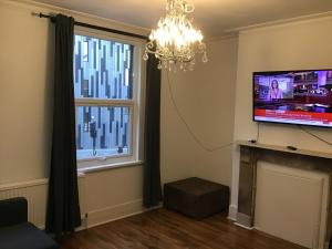 ein Wohnzimmer mit einem Flachbild-TV und einem Kronleuchter in der Unterkunft Residential Quarters, General Gordon Square in London
