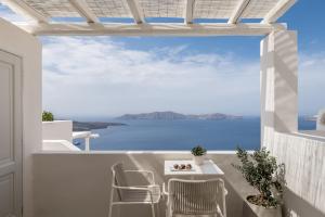 einen Balkon mit einem Tisch und Stühlen sowie Meerblick in der Unterkunft Enigma Suites in Fira