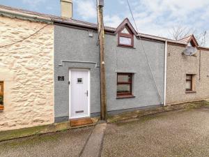 a gray house with a white door on a street at 2 Ysgoldy in Bangor