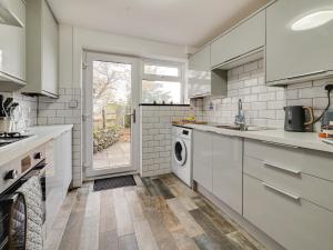 a kitchen with white cabinets and a washer and dryer at 2 Ysgoldy in Bangor