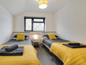 two beds in a room with yellow sheets at 2 Ysgoldy in Bangor