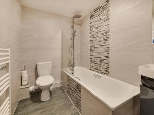 a bathroom with a toilet and a tub and a sink at 2 Ysgoldy in Bangor +9 photos
