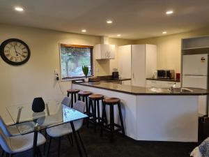 a kitchen with a bar with stools and a clock on the wall at Rainforest Retreat in Franz Josef