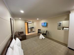 ein Hotelzimmer mit einem Bett und einem Wohnzimmer in der Unterkunft Balranald Club Motel in Balranald