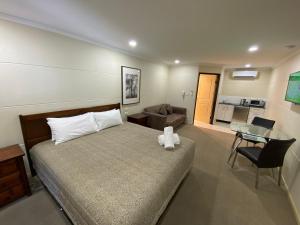 ein Schlafzimmer mit Bett und ein Wohnzimmer in der Unterkunft Balranald Club Motel in Balranald