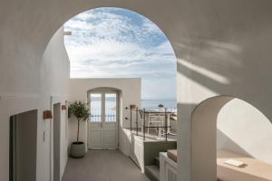 an archway leading to a balcony with a view of the ocean at Enigma Suites in Fira