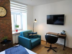 Cette chambre comprend une chaise bleue, un bureau et une horloge. dans l'établissement theApartments Radwańska, à Łódź