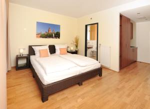 Schlafzimmer mit einem Bett mit weißer Bettwäsche und orangefarbenen Kissen in der Unterkunft GuestHouse Mainz in Mainz