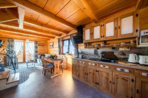 a kitchen with wooden cabinets and a table in a room at Domki Widokowe Wooden Pod Gubałówką z Jacuzzi in Ząb