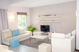 Una sala de estar con muebles blancos y un televisor de pantalla plana. en Exclusive penthouse with paradise sea view, en Grand Baie