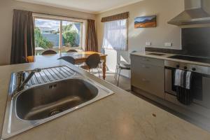 a kitchen with a sink and a table at Leigh Cottage Manapouri in Manapouri