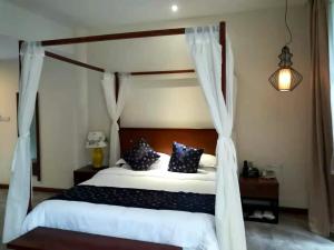 a bedroom with a canopy bed with blue and white pillows at Guilin Crystal Crescent Moon Hotel in Guilin