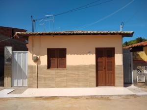 una pequeña casa con puertas marrones en una calle en Cantinho Morro Branco, en Beberibe