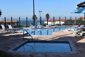 a swimming pool with lounge chairs and an empty swimming pool at La Paloma Beach&Tennis Resort in Rosarito