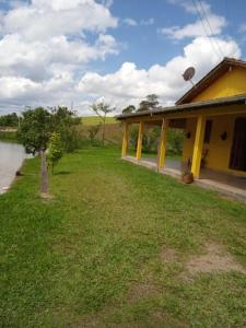 ein gelbes Haus mit einem Hof neben einem Fluss in der Unterkunft Sítio Elias in Lauro Müller