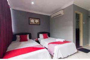 two beds in a room with red and white sheets at Puteri Ampang Hotel in Ampang