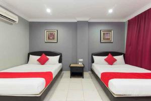 duas camas num quarto de hotel com almofadas vermelhas em Puteri Ampang Hotel em Ampang