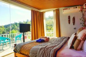 a bedroom with a bed and a balcony with a television at La Niebla Farm Resort in Ooty