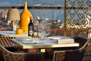 una mesa con botellas de vino y copas en el balcón en Hôtel Fesch & Spa, en Ajaccio