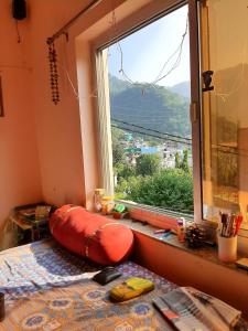 a bedroom with a large window and a bed with a pillow at Tebaar Backpackers in Rishīkesh +22 photos