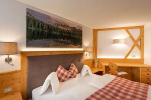 una camera d'albergo con un letto e una grande finestra di Majon d'Aisciuda a Vigo di Fassa
