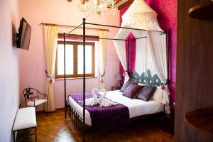 a bedroom with a four poster bed with purple sheets at Posada La Fabula in Santillana del Mar