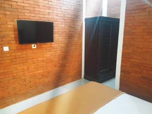 a room with a brick wall with a flat screen tv at Tobana Pejaten House in Jakarta +7 photos