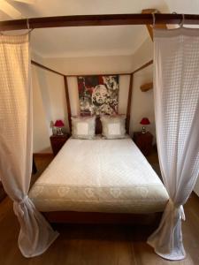 1 dormitorio con cama con dosel y cortinas blancas en Chambres Les Plantous de Severo, en Cénac-et-Saint-Julien