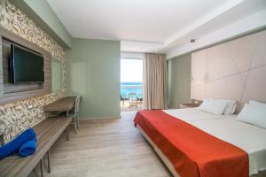 a hotel room with a bed and a flat screen tv at Pegasos Deluxe Beach Hotel in Faliraki
