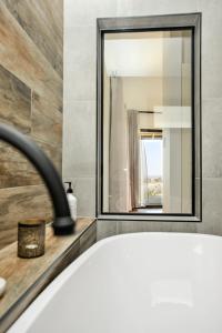 a bathroom with a white tub and a mirror at Old Bull Creek Luxury Retreat in Strathalbyn