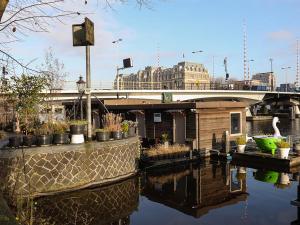 ein Gebäude mit Pflanzen und einer Brücke über einen Fluss in der Unterkunft Houseboat Little Amstel in Amsterdam