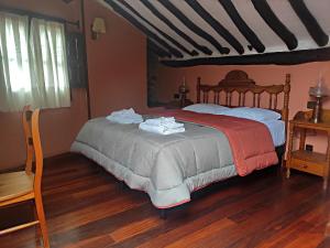 een slaapkamer met een bed en een houten vloer bij Posada de Candelario in Candelario