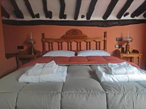 1 dormitorio con 1 cama grande con almohadas blancas en Posada de Candelario, en Candelario