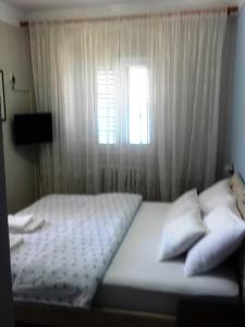 a bedroom with a bed with a window and white curtains at Pana-Eustahije 253 in Kotor