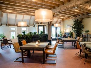 un restaurante con mesas, sillas y plantas en De Raayhof, en Pannerden