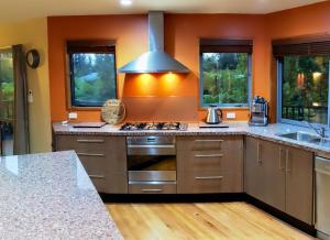 uma cozinha com paredes cor de laranja e um forno com placa de fogão em The Ferns Hideaway em Franz Josef