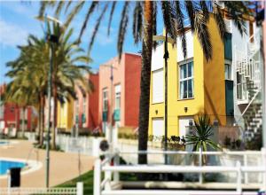 a white bench in front of a building with palm trees at Tu Hogar en Verazul in Vera
