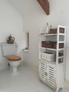 a bathroom with a toilet and a shelf with baskets at Luxury barn conversion near Salcombe & Kingsbridge, South Devon in Kingsbridge