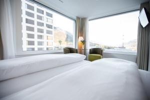 Mercure Chur City West في شور: سريرين في غرفة الفندق مع نافذة كبيرة