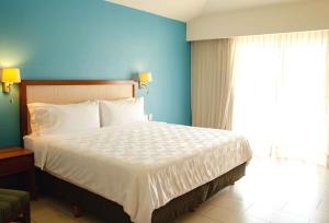 a bedroom with a large bed with a blue wall at Holiday Inn Huatulco, an IHG Hotel in Santa Cruz Huatulco