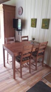 einem hölzernen Esstisch mit Stühlen und einem TV in der Unterkunft Pension Waldfrieden in Maring-Noviand