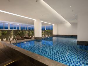 una piscina en un hotel con azulejos azules en favehotel Karawang, en Karawang