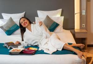 een vrouw op een bed met een dienblad met eten bij Novotel Cairo Airport in Caïro