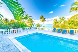 a pool with chairs and the ocean in the background at Butterfly Cottage at Viking Hill - Love Beach in Nassau