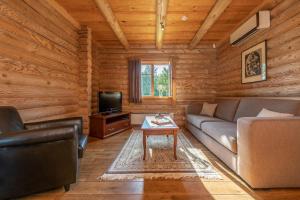 a living room with a couch and a tv in a log cabin at Alauso Slenis in Sudeikiai