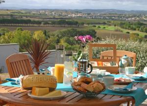 a table with a breakfast of cheese and bread on it at B&B-Les Balcons de Maragon in Carcassonne