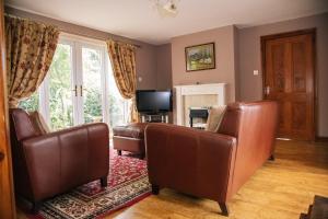 uma sala de estar com cadeiras de couro e uma televisão em Millmoor Farm Holidays em Malpas