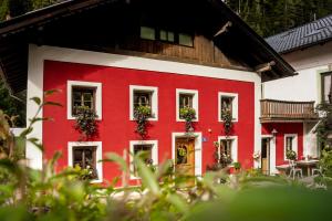 a red and white house with plants on the windows at Gabis kleine Spezerey in Gries am Brenner